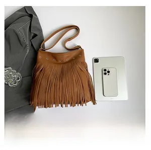Close-up of brown fringe shoulder bag featuring metal rivet details and faux leather texture