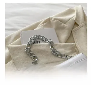 Detailed close-up of white crocodile pattern shoulder bag with chunky silver metal chain