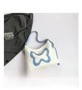 Detailed shot of white hobo bag with blue butterfly patch and silver metal rivets