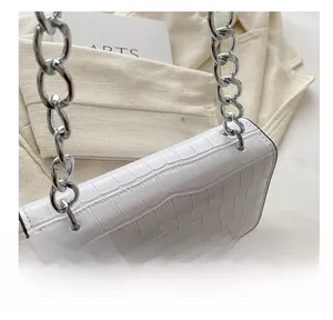 Detail of white crocodile texture handbag with chunky silver chain on neutral background