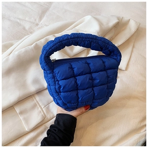Detail of blue quilted cloud bag showing soft padded texture and top zipper closure