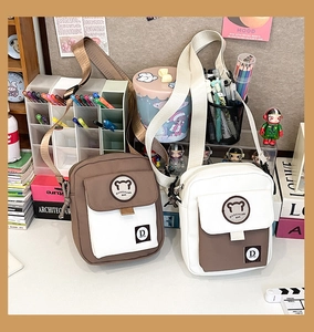 Detail view of contrast color canvas crossbody bags with adjustable straps and bear logo