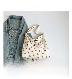 Close-up of cream corduroy tote bag with strawberry print and black drawstring detail
