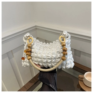 Detail of white bubble pleated handbag featuring unique wooden and amber bead handle straps