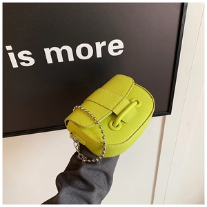 Detail of neon green litchi texture leather saddle bag with silver metal ball chain