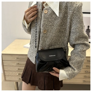 Détail d'un sac bandoulière plissé noir avec chaîne et inscription Fashion & Bag
