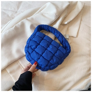 Detail of Klein Blue quilted puffer bag texture placed on a beige blazer jacket