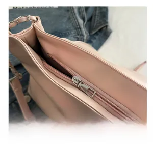 Dettaglio della cerniera in metallo argentato e tracolla a catena di una borsa rosa chiaro