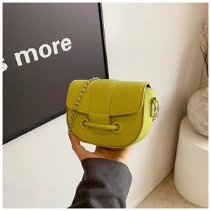 Detail view of the lime green pebble leather saddle bag with silver ball chain strap