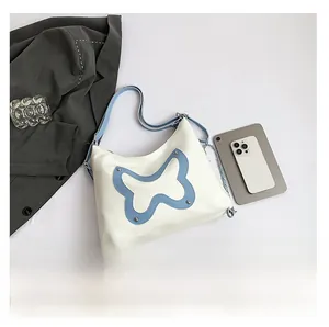 Detailed flat lay of a white hobo bag with blue butterfly patch and dual straps