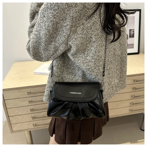 Détail du sac nuage noir plissé avec bandoulière chaîne sur une veste en tweed