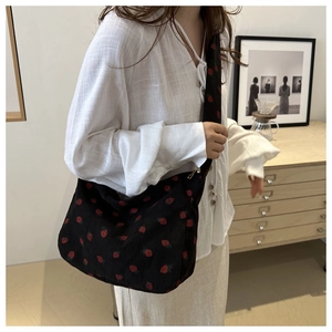 Détail du sac hobo en velours noir avec motif fraise et large bandoulière