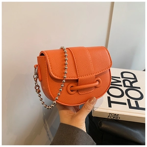 Close-up of orange saddle bag with lychee grain texture and silver bead chain strap