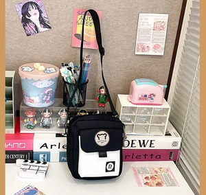Detail view of black and white canvas crossbody bag with cute bear patch and nylon strap