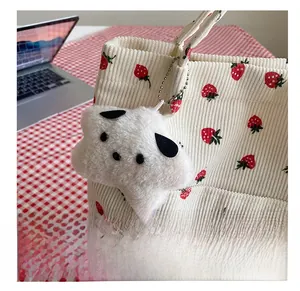 Detail of cute plush dog pendant on strawberry print corduroy tote bag with bead chain