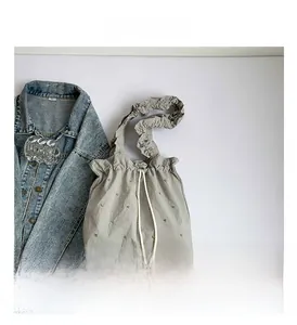 Close-up of pleated gray tote bag with white drawstring closure and eyelet details