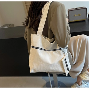 Detail of white wrinkled texture tote bag with a matching small zipper pouch on shoulder