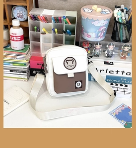 Detail view of a compact white and brown bear pattern crossbody bag with a wide strap
