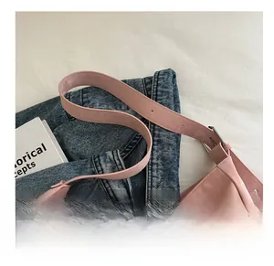 Detail of pink leather bag shoulder strap with silver metal buckle on denim fabric
