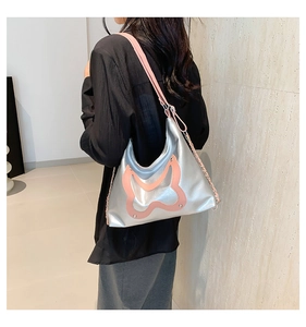 Detail of silver metallic crossbody bag featuring large pink butterfly applique and chain