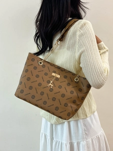 Schicke braune Leder-Tragetasche mit Vintage-Muster und Goldkettenriemen am Modell