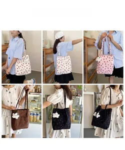 Detail of printed corduroy tote bag with strawberry pattern and plush cloud pendant charm