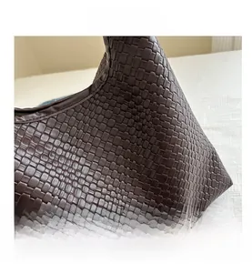 Close-up of the dark brown woven texture and intricate leather detail on the handbag