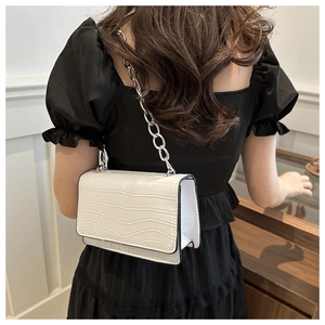 Close-up of pearl white crocodile embossed faux leather bag with silver chain strap detail