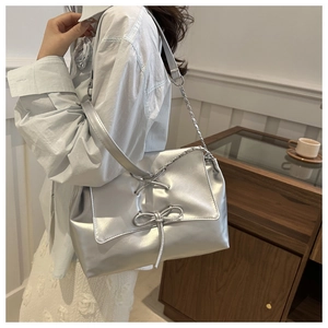 Borsa a tracolla argento metallizzato con fiocco e catena, indossata a spalla