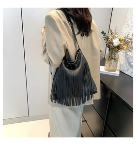 Detail of black pebbled leather tote featuring stylish long fringe and golden hardware