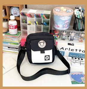 Close-up of black and white canvas bag featuring a cute bear embroidery and adjustable strap