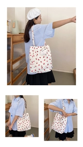 Detail of white corduroy tote bag with strawberry prints and cute white bear charm
