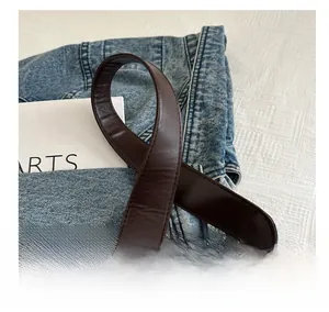 Detail of coffee brown leather shoulder strap featuring woven ends for a retro tote bag