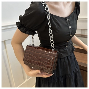 Detail of dark brown faux crocodile leather shoulder bag with silver chain strap