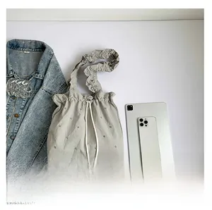 Detail view of grey pleated tote bag with pearls shown with daily lifestyle essentials