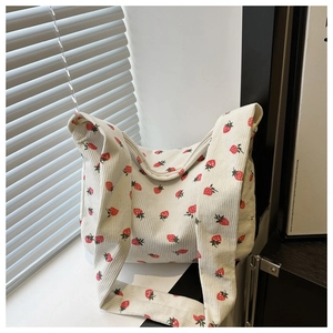 Gros plan d'un sac cabas en velours côtelé crème avec motifs fraises et texture côtelée