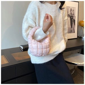 Pink quilted cloud handbag with soft padding texture paired with a beige knit sweater