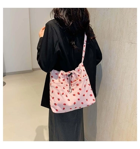 Detailed side view of pink corduroy strawberry print tote bag with drawstring closure