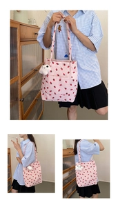 Detail of pink corduroy tote bag with strawberry print and white plush charm