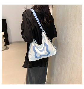 Close-up of white tote bag with blue butterfly patch and stylish wide shoulder strap