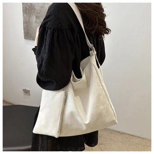 Detail view of the white faux leather tote bag showing smooth texture and side zipper design