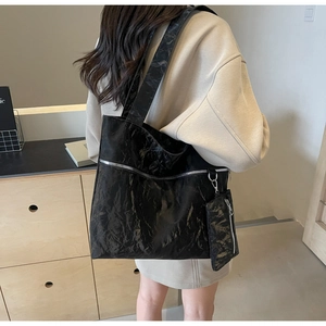 Detail of black tote bag with unique crinkled texture, silver zipper, and mini pouch