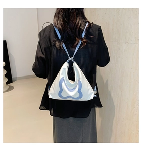 Detail of a white and light blue bow tote bag worn by a model to show actual product size