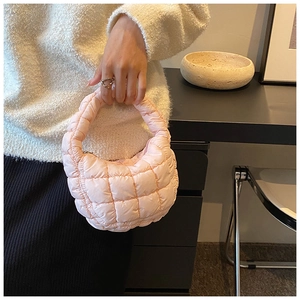 Macro detail of a mini light pink quilted puffy handbag with high-quality stitching and texture