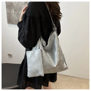 Detail of silver metallic tote bag featuring matching pouch and adjustable strap texture