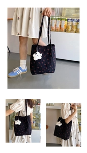 Detail of black corduroy tote bag with red strawberry print and cute plush cloud charm