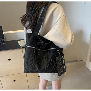 Detailed look at the large black pleated tote bag with silver zipper and mini pouch on model