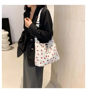 Detail of white corduroy tote bag with red strawberry print and black drawstring closure