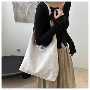 Detail of white woven hobo tote bag texture and wide strap on model shoulder