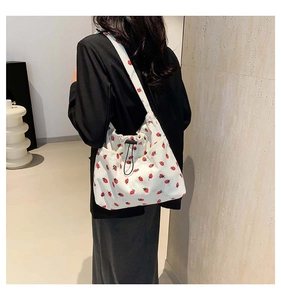 Detail of white corduroy tote bag with red strawberry print and drawstring closure